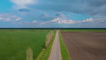 Country Road With Gray Asphalt And White Lines Of Markups Between Agricultural Fields Under Sky With Rainy Dark Clouds . Way Safety And Cargo Transportation Concept