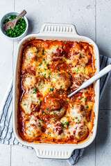 Wall Mural - Baked cheesy meatballs casserole with tomato sauce in the oven dish, top view.