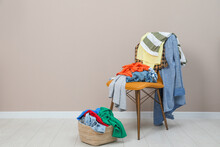 Orange Chair And Wicker Basket With Different Clothes Near Light Grey Wall, Space For Text
