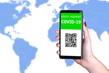 Female hand holding  new immunity covid-19 health passport on world background. Documents needed to journey after being vaccinated. Documented vaccine administration against coronavirus to fly safe.