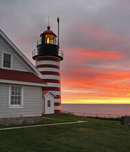 Sunrise Accents The Red And White Striped West Quoddy Head Lighthouse In Lubec Maine.