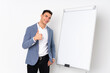 © luismolinero - Young caucasian handsome man isolated on purple background giving a presentation on white board and with thumbs up