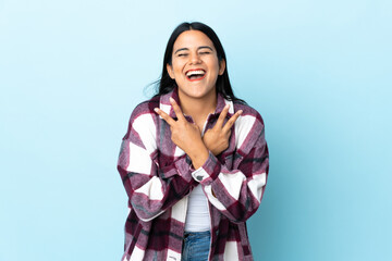 Wall Mural - Young latin woman woman isolated on blue background smiling and showing victory sign