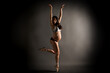 Young Hispanic pregnant ballerina performing classical ballet pose with sequin top in the studio