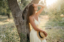 Portrait Of Beautiful Young Brunette Woman In Straw Hat At Sunset In Olive Garden. Travel To Italy, Summer Vacation