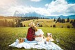 Romantic couple on vacation visiting italian dolomites alps - Man and woman having fun together sitting on a hill 