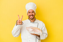 Young Caucasian Chef Man Holding Chicken Isolated On Yellow Background Showing Number Two With Fingers.