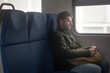 © Olga - a man with a backpack sits on a seat in an electric train with a ticket in his hands