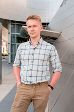 A Young Blond Man In A Shirt Poses In Business Style In The Metal Walls Of The Walt Disney Concert Hall. A Popular Destination For Sightseeing In Los Angeles, California.