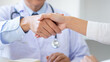 Doctor reassuring trust to patient by holding hand at hospital.