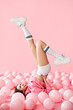 © GVS - Young pretty woman have fun with legs up lying in pink balloons over pink pastel background