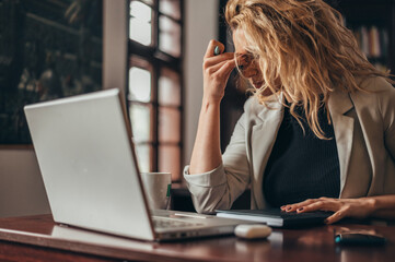 Businesswoman being tired while working on a laptop in her office