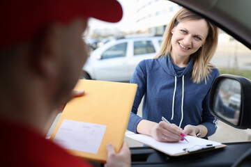 Female client puts signature on documents when receiving parcel from courier