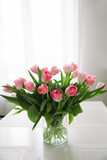Fototapeta Tulipany - Bouquet of pink tulips in a transparent vase, on kitchen table. Flowers in interior.