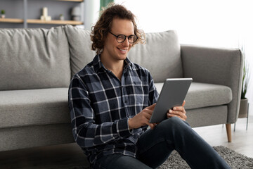 Poster - Happy Millennial Man Using Digital Tablet Browsing Internet At Home