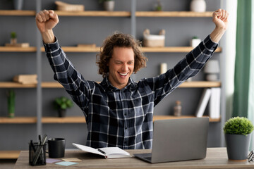 Poster - Joyful Young Businessman At Laptop Shaking Fists Sitting In Office