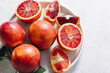 Whole and sliced blood oranges in a plate on white table background. Flat lay, top view, copy space.