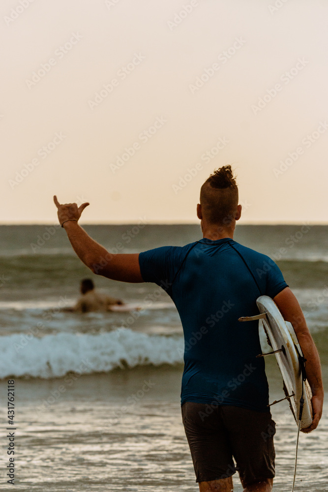 Surfer z deską surfingową na tle oceanu, mężczyzna uprawiający zdrowe sporty wodne. - obrazy, fototapety, plakaty 