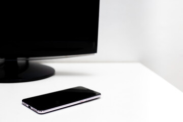 Smartphone and screen of computer on the white desk with copy space.