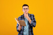 © Prostock-studio - Pensive student in casual wear reading textbook, thinking over complicated task, studying for exam on orange background