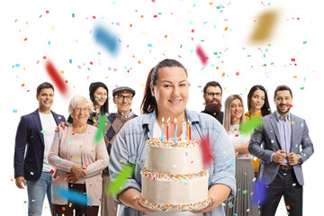 Wall Mural - Corpulent young woman holding a birthday cake and people standing behind at a celebration