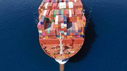 Aerial drone photo of truck size container cargo vessel cruising in deep blue Saronic gulf near commercial port of Piraeus, Attica, Greece