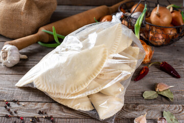 Frozen chebureks in the bag on a table with ingredients. Traditional homemade food.