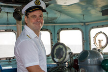 A Captain Standing In The Wheelhouse Of Ship And Looking To Camera.