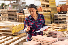 Female Worker With Tablet Checking Quantity Of Paving Slabs In Warehouse Of Building Materials