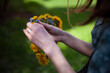 Girl in a blue dress in a wreath with yellow dandelions on his head