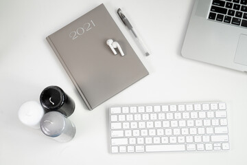 office flat lay: computer, modern keyboard, notebook, wireless headphones, candles on white office table