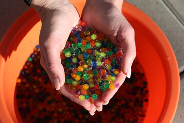 Wall Mural - Top view of hands holding small colorful plastic balls