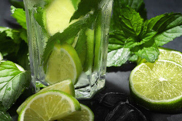 Wall Mural - Fresh homemade mojito cocktail with lime, mint and ice on a black background, close-up