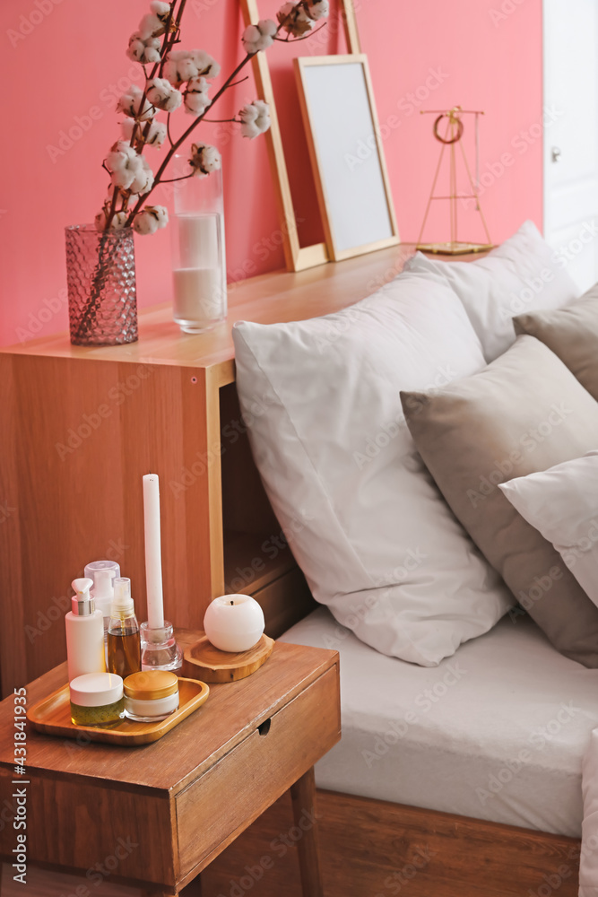 Candles and cosmetics on bedside table in bedroom