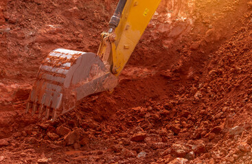 Backhoe working by digging soil at construction site. Bucket of backhoe digging soil. Crawler excavator digging on dirt. Closeup backhoe bucket of yellow backhoe. Earthmoving. Trenching machine.