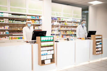 Wall Mural - Pharmacy interior with medicines and pharmacist cashiers working during corona virus pandemic.