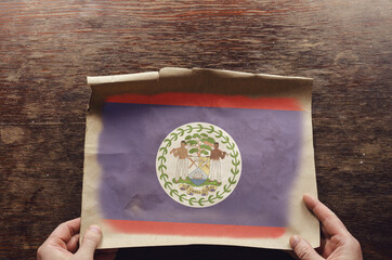 The blue and red Belize National Flag on a tattered piece of paper.