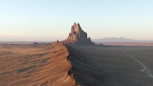 Aerial Shot Of Rocky Mountain In Desert Against Sky During Sunset, Drone Ascending Over Arid Landscape - Shiprock, New Mexico