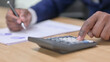 © stockbakers - African Businessman Using Calculator for Paperwork, Financial Documents