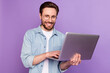 © deagreez - Photo of happy cheerful smiling handsome businessman in glasses working in laptop isolated pm violet color background