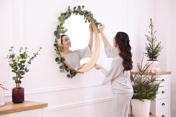 Wall Mural - Woman decorating mirror with eucalyptus branches at home