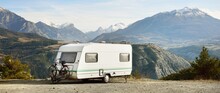 Caravan Trailer, Bicycle And Car Parked On A Mountaintop With A View On French Alps Near Lake Lac De Serre-Poncon. Transportation, RV, Motorhome, Road Trip, Camping, Tourism, Recreation, Lifestyle
