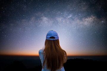 silhouette of young woman looking beautiful view of night sky and star and milky way alone on top of