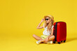 excited little girl with suitcase and passport sitting on floor