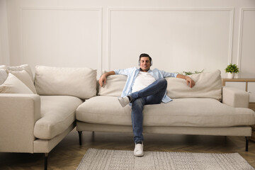 Canvas Print - Man with headphones sitting on comfortable sofa in living room