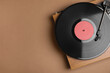 Modern vinyl record player with disc on brown background, top view. Space for text