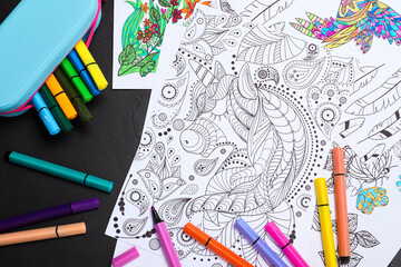 Poster - Antistress coloring pages and felt tip pens on black table, flat lay