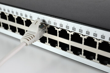 Closeup view of network switch with cable on light background. Internet connection