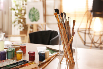 Sticker - Paints and brushes on wooden table in art studio