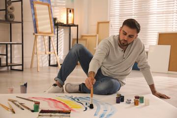 Poster - Young man painting on canvas with brush in artist studio